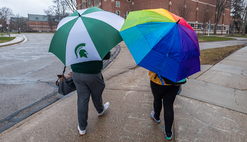 Two students holding umbrellas