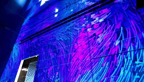 Large-scale art on a wall features pink, purple and blue lights.
