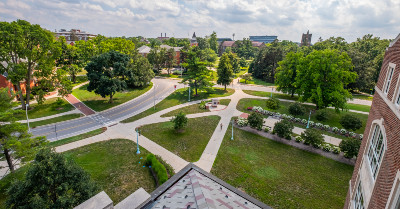 A view of campus with green grass and trees from the top of a parking structure.