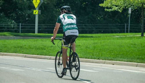 A bicycle rider wearing MSU gear.
