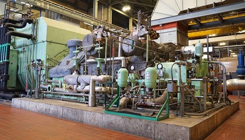 Industrial equipment and pipes surround a steam boiler.