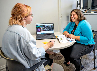 A student and adviser sit at a table talking.